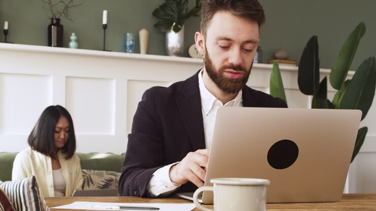 Geschäftsmann sitzt am Tisch und nutzt einen Laptop.