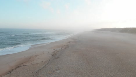 aerial video of waves on a long sandy beach at sunrise