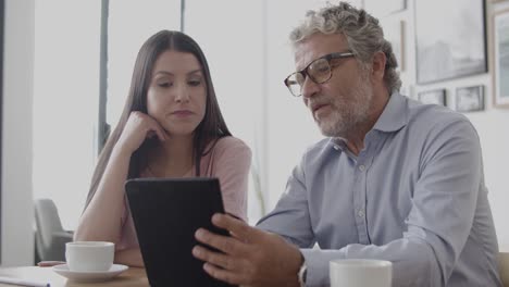 brunette businesswoman sitting at table and talking with senior worker