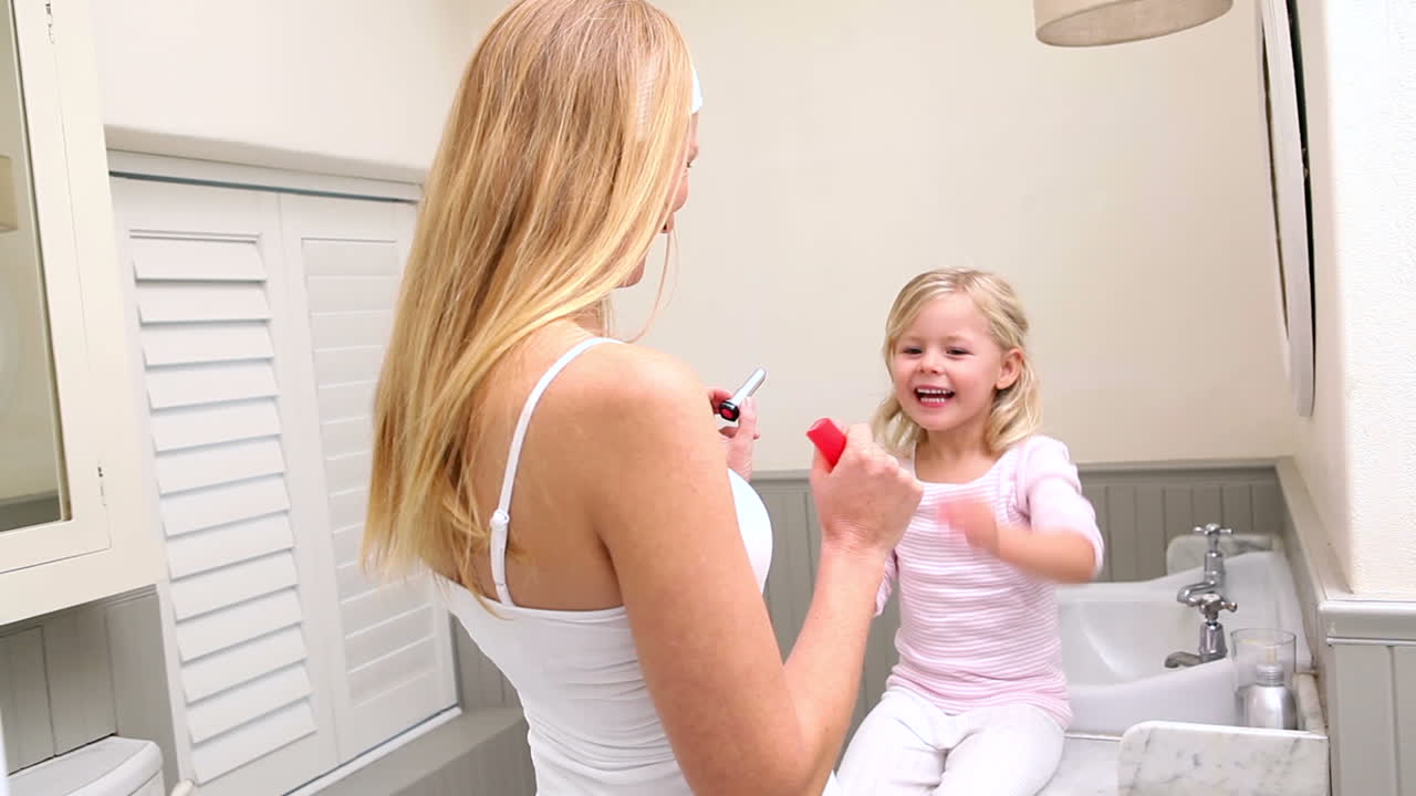 Mother putting lip gloss on little daughter