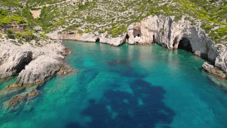 rocky coastline with people swimming in blue water