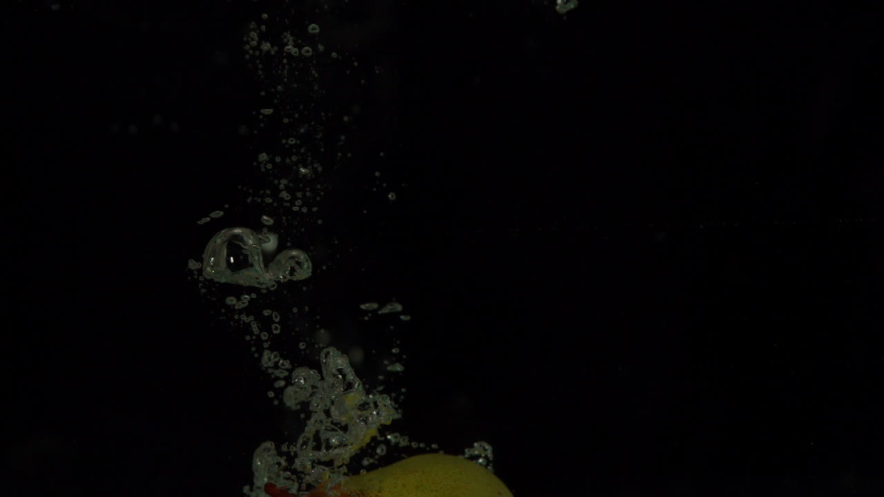 pera sumergiéndose en el agua sobre un fondo negro