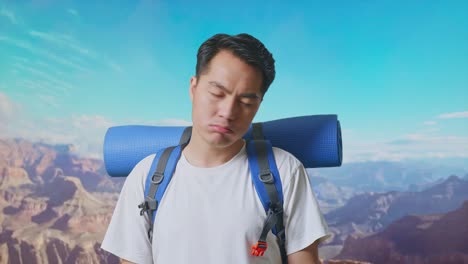 close up of asian male hiker with mountaineering backpack shaking his head and making unsatisfied face while traveling at the top of mountain