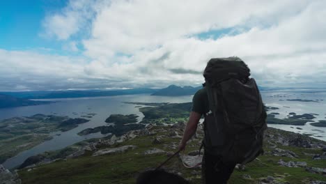 lurøyfjellet mountain peak with a guy and dog trekking in lurøya island, nordland county, norway