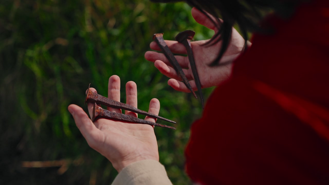 closeup of open hands of Jesus Christ holding four rusty iron crucifixion nails