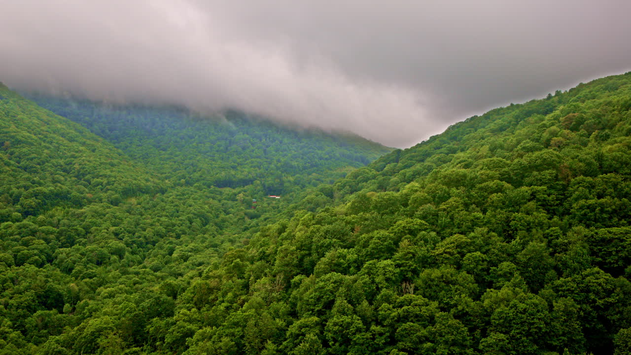 Sweeping aerial drone view of mist drifting through the Smokies