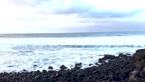 Rocky-beach-white-foamy-waves,-slow-motion-panning-shot