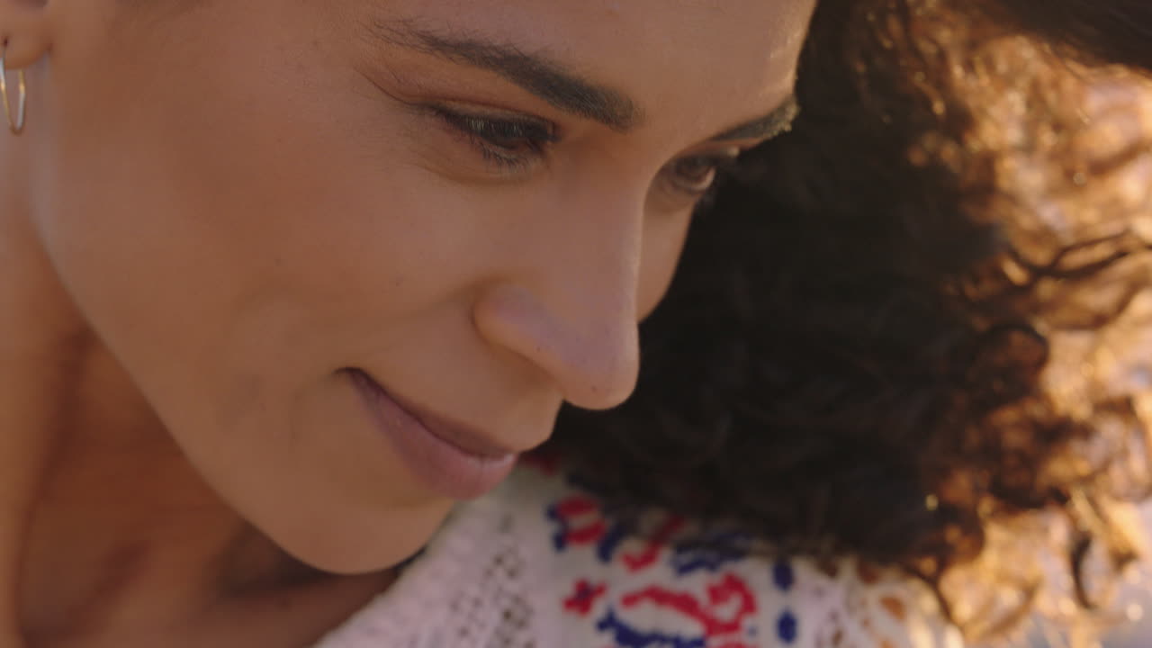 retrato en primer plano de una hermosa mujer feliz disfrutando de la libertad explorando la espiritualidad sintiendo alegría en una playa pacífica al atardecer con el pelo soplado por el viento