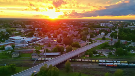 Luftaufnahme-Einer-Stadt-Bei-Sonnenuntergang-Mit-Zügen-Und-Bahngleisen-Im-Vordergrund