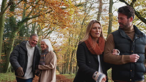 senior couple walking along path through autumn countryside with adult offspring