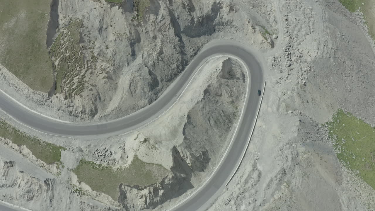 Curvy mountain road with a car driving through a remote landscape in Kyrgyzstan
