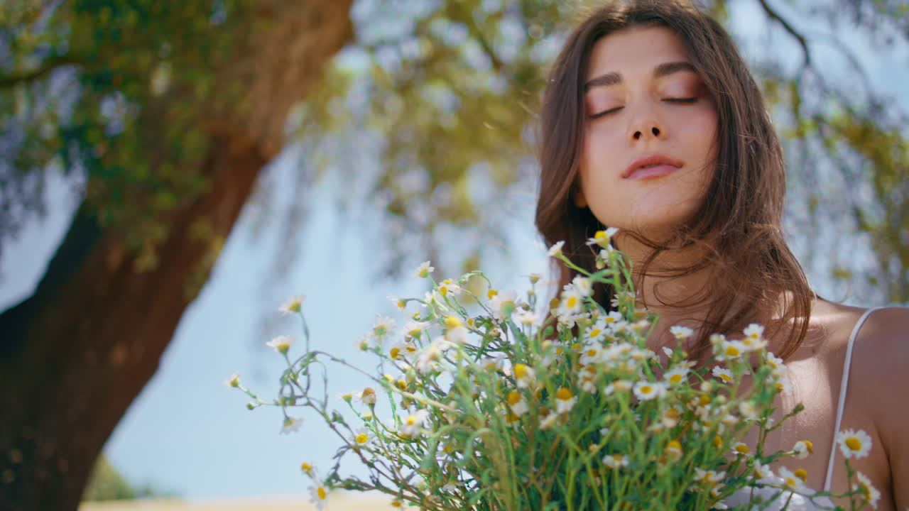 Rural girl touching hair hold wildflowers closeup. Happy woman enjoying bouquet