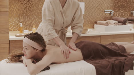 masajista haciendo masaje de espalda para una mujer joven