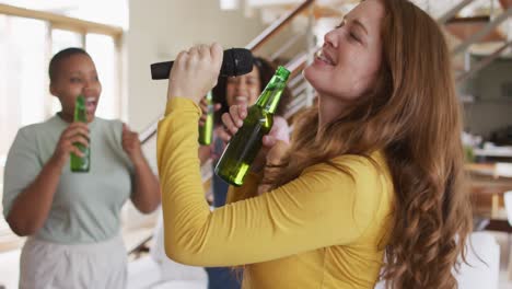 diverse group of female friends having fun singing karaoke and drinking beer at home