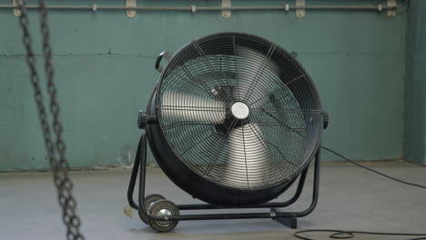 industrial chain swinging in front of a big spinning fan