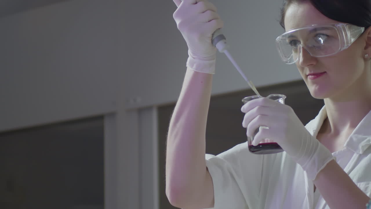 Young female scientist using pipette for blood in laboratory, middle shot view