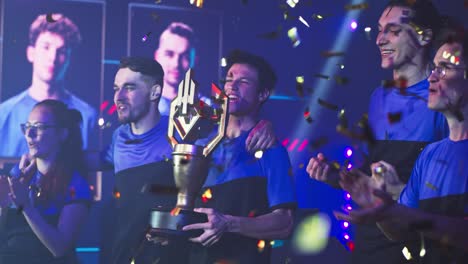 team of gamers with golden cup celebrating victory