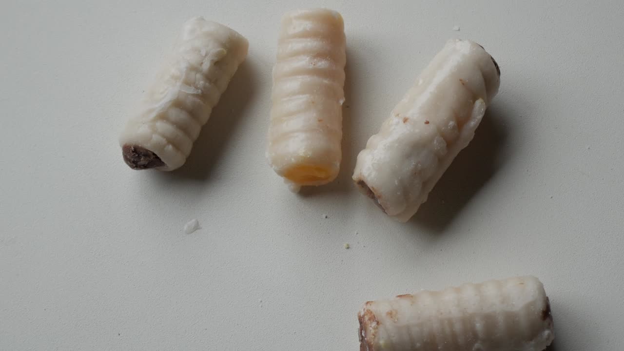 Close-up zooming Spain's traditional sweet for All Saint's Day, Saint's bones (Huesos de Santo), made from marzipan and different fillings.