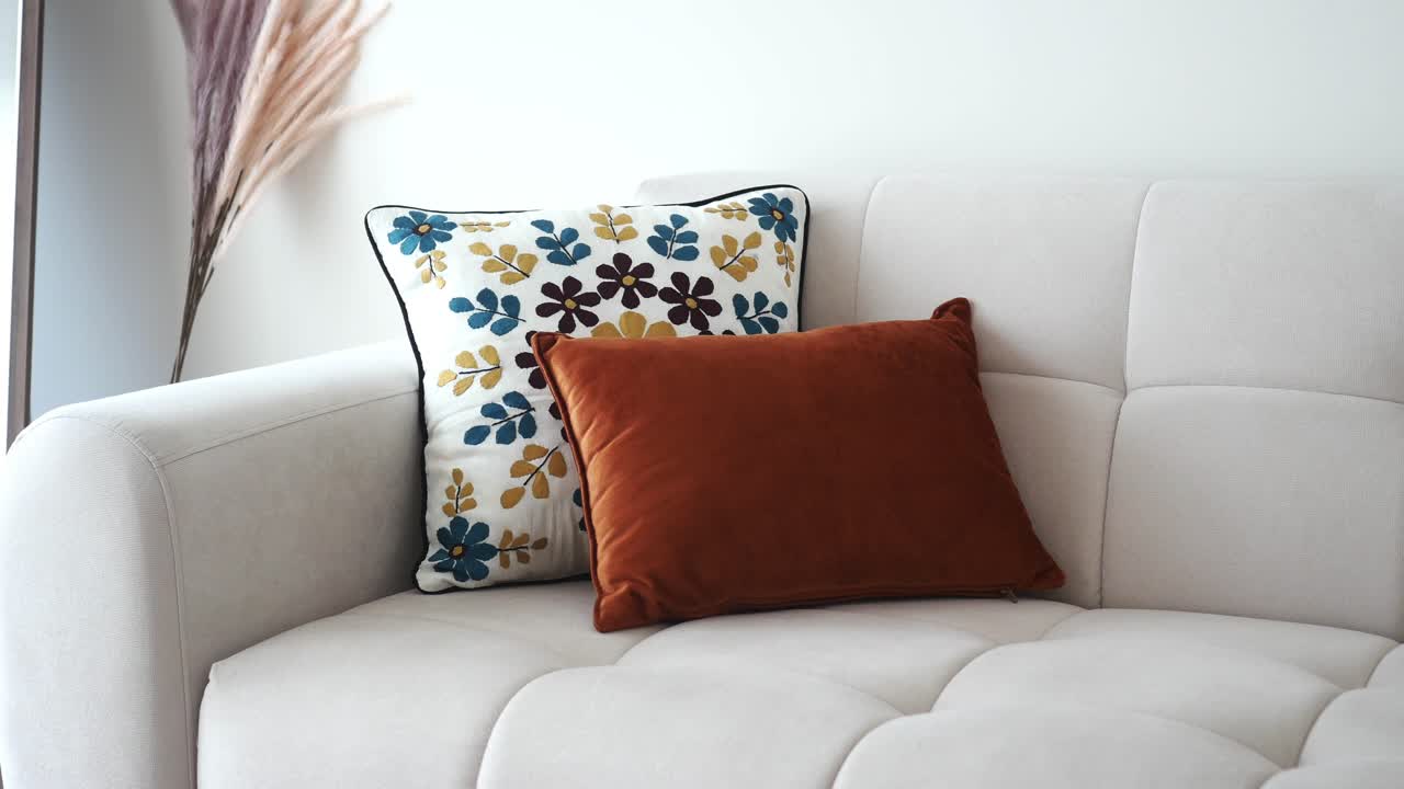 un sofá blanco con una almohada de lanzamiento de patrones florales y una almohadilla de terciopelo marrón