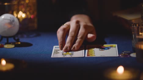 primer plano de una mujer dando lectura de cartas de tarot en una mesa a la luz de las velas 16