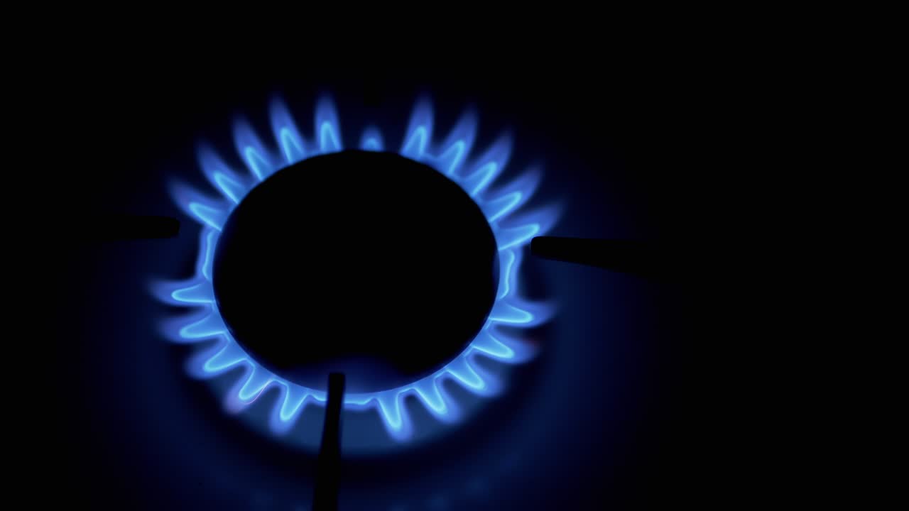 газовый горелок, светящийся синим пламенем, ночью на кухне. крупный план
