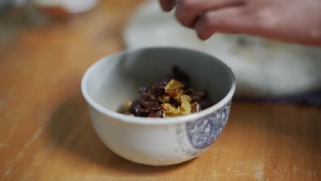 freshly soaked and diced raisins and berries moved from marble cutting board into bowl, filmed as close up slow motion shot