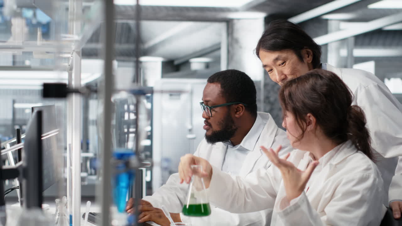 Vertical video Multiracial researchers in lab inspecting liquids in test tube