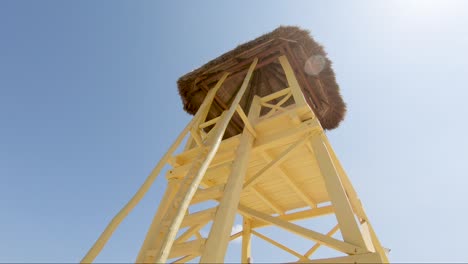 Looking-up-at-a-bright-yellow-rescue-tower-on-a-tropical-beach