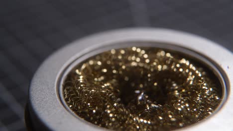 cleaning the tip of the soldering iron in some brass wool