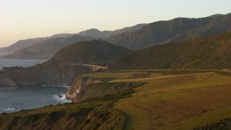 scenic aerial of big sur’s coastline with bixby bridge and highway 1 curving above dramatic pacific cliffs. a breathtaking blend of rugged terrain, iconic infrastructure