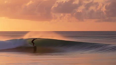 a surfer rides a wave in the ocean during a beautiful sunset or sunrise