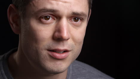 studio shot of tearful man against black background