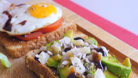 buen primer plano de huevo frito casero en una tostada con rodajas de tomate y tostadas de aguacate en una tabla de cortar de madera