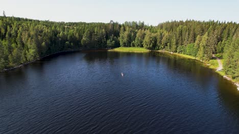 aerial view of a person kayaking on a calm lake surrounded by a lush green forest