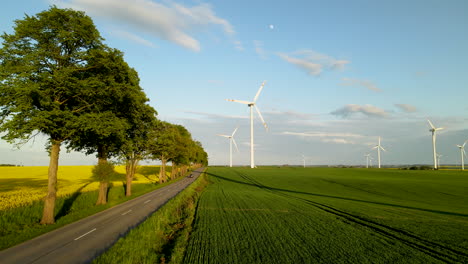 Luftaufnahme-Des-Windturbinenparks-Und-Des-Autofahrens-Auf-Der-Straße-Während-Des-Schönen-Sonnenuntergangs-In-Polen