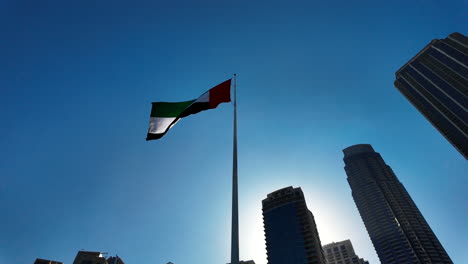 uae flag flying high above dubai cityscape