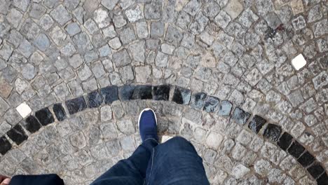 person walking on a patterned cobblestone path