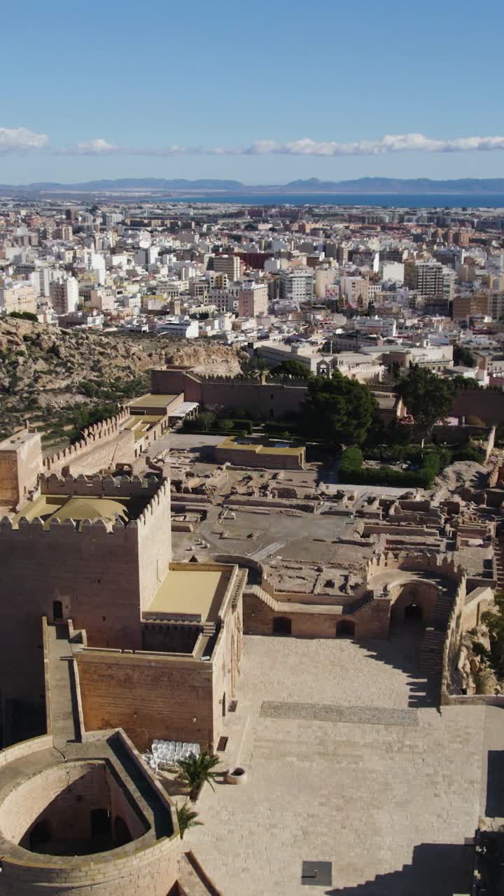 Sorvolo aereo verticale che mostra le mura fortificate dell'Alcazaba di Almería con il paesaggio urbano sullo sfondo, Andalusia, Spagna