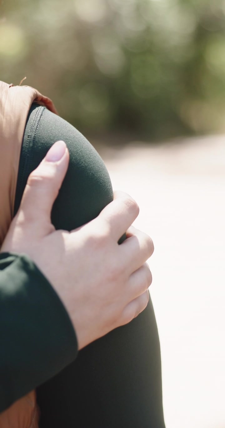 Primo piano di una persona che si tiene la propria spalla all'aperto