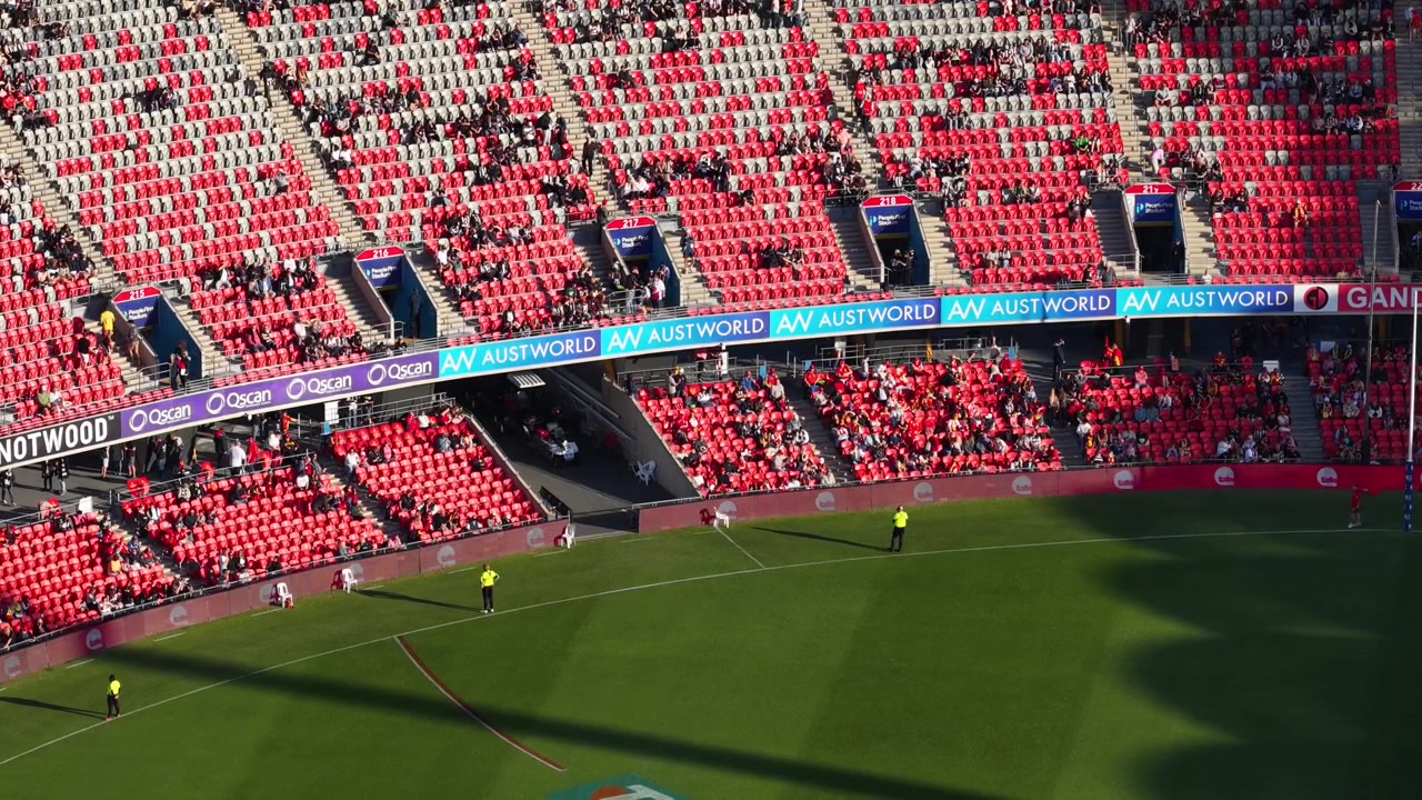 Høyt vinkelperspektiv av fans sittende på røde tribuner med utsikt over en grønn idrettsbane