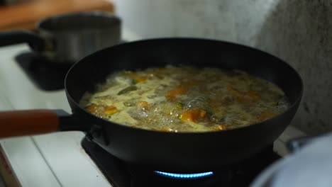 lid open and close for pan of delicious pumpkin soup bubbling and boiling in frying pan, filmed as medium closeup shot in slow motion