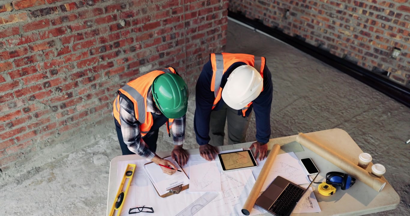 Construction Engineers Reviewing Blueprints and Tablet at Building Site