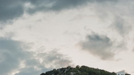 Nubes-Oscuras-Moviéndose-Sobre-Una-Montaña-Rocosa-Verde---Lapso-De-Tiempo