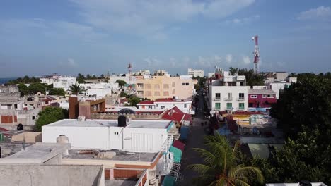 una toma inclinada de casas de la ciudad entre árboles con follaje colorido y cielo azul durante el día en isla mujeres méxico