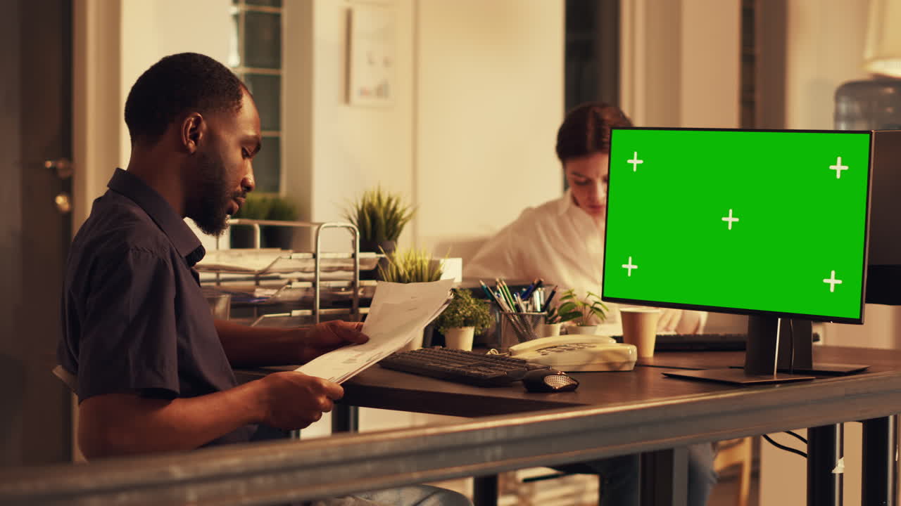 Male manager looking at computer with greenscreen display