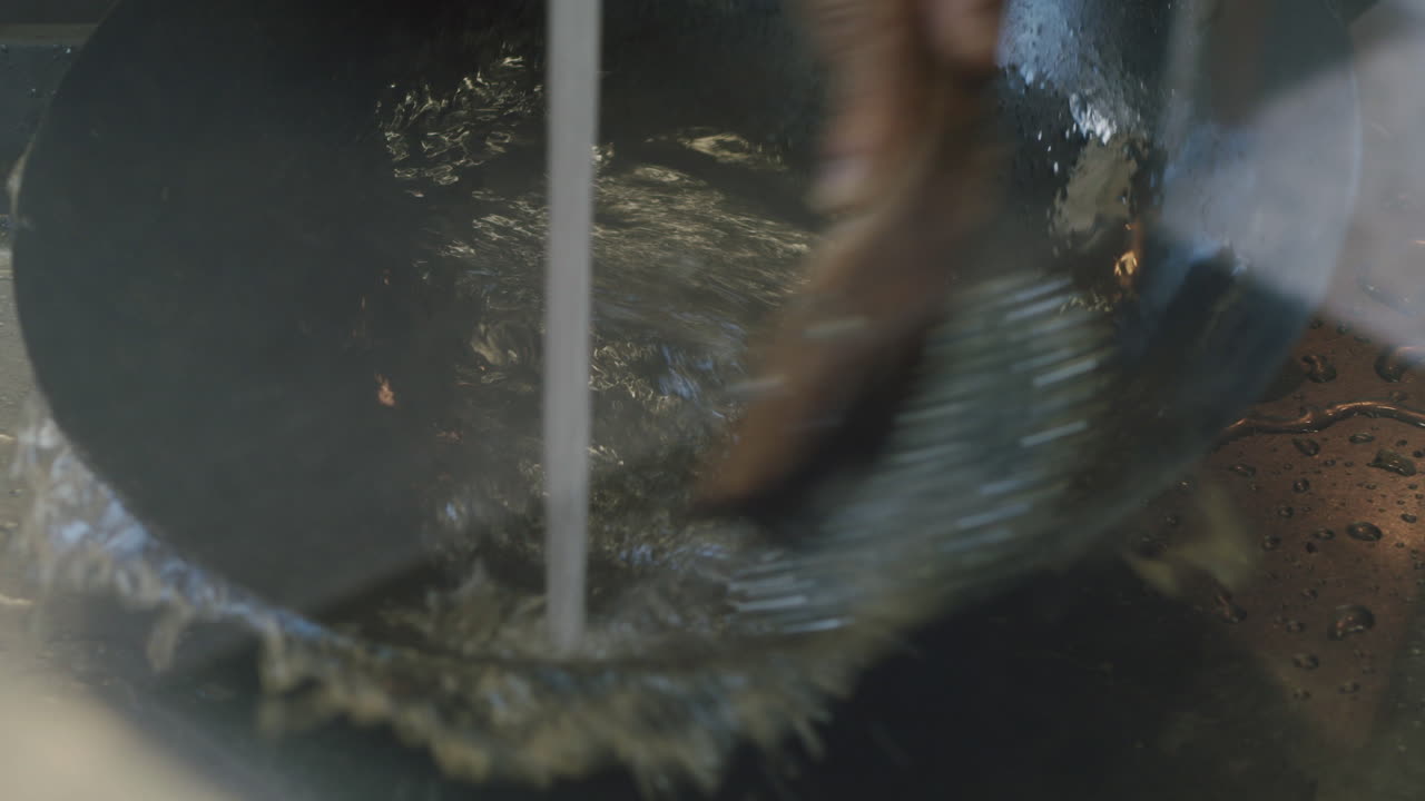 A wok pan is cleaned. The footage is in slow motion.