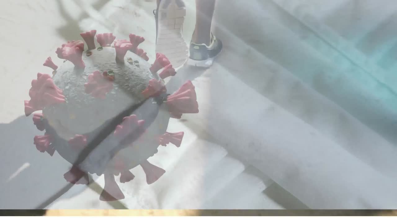 해변에서 달리는 여성의 낮은 부분에 대해 회전하는 코로나19 세포의 디지털 복합 비디오