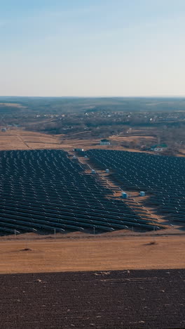 aerial view of back side solar panels stand in a row in the autumn fields green energy at sunset landscape. solar power plant in the countryside. vertical video