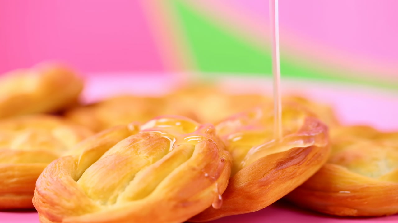 Honey Drizzle On Golden Danish Pastries, Bakery Showcase With Pink Backdrop And Green Accent, Closeup Of Flaky