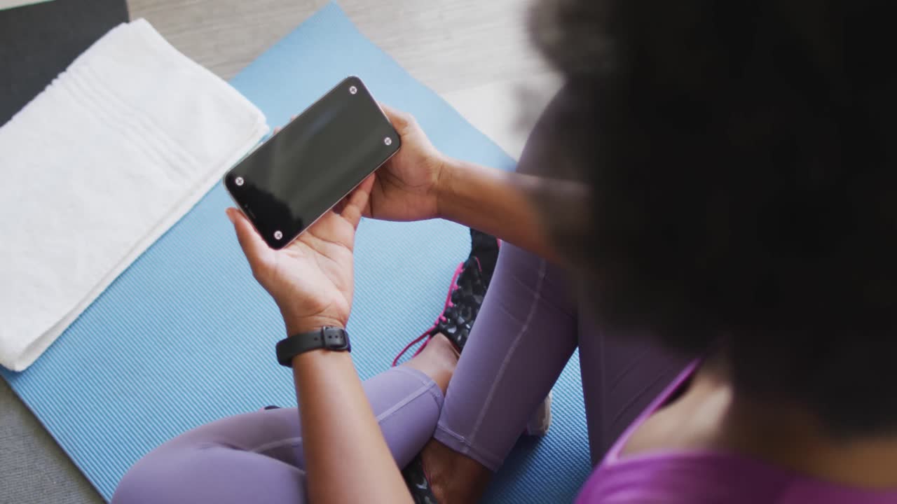 feliz afroamericano usando ropa deportiva, haciendo ejercicio, usando un teléfono inteligente con espacio para copiar